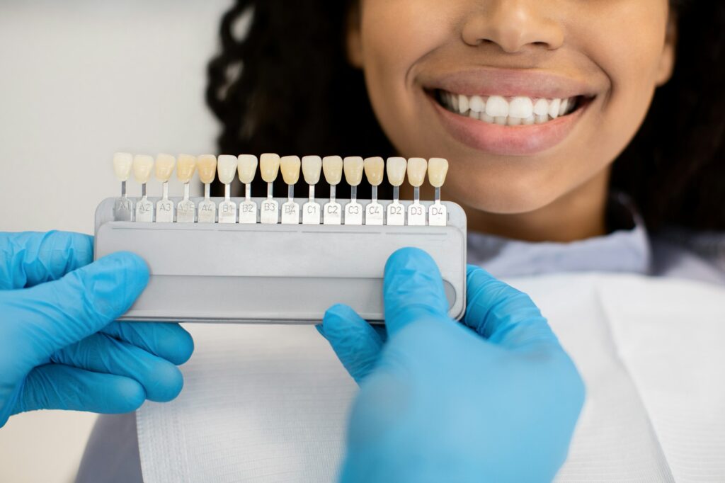 Stomatologist Holding Dental Teeth Shade Guide Chart Choosing Color For Female Patient